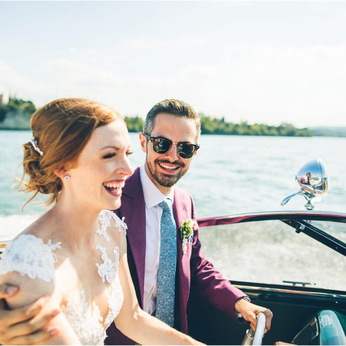 Bride and Groom on a Riva speedboat, smiling with the sun in the background. Lake Garda