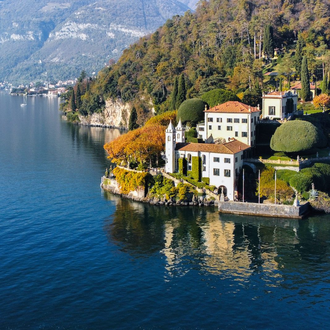 Villa Balbianello Lake Como, surrounded by autumn trees and mountains in the background.